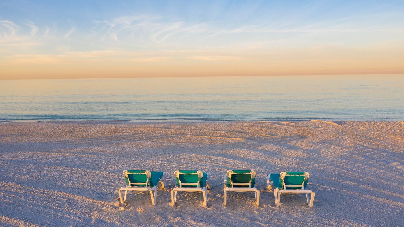 Beach chairs on white Gulf sand at sunrise