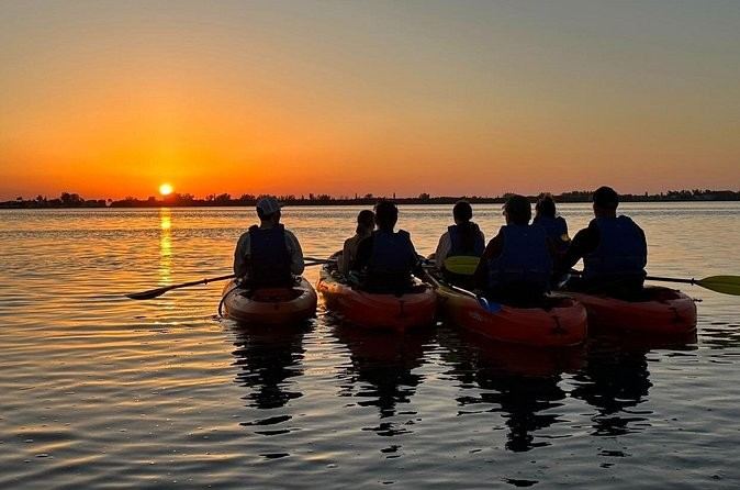 Kayakers paddling at sunset
